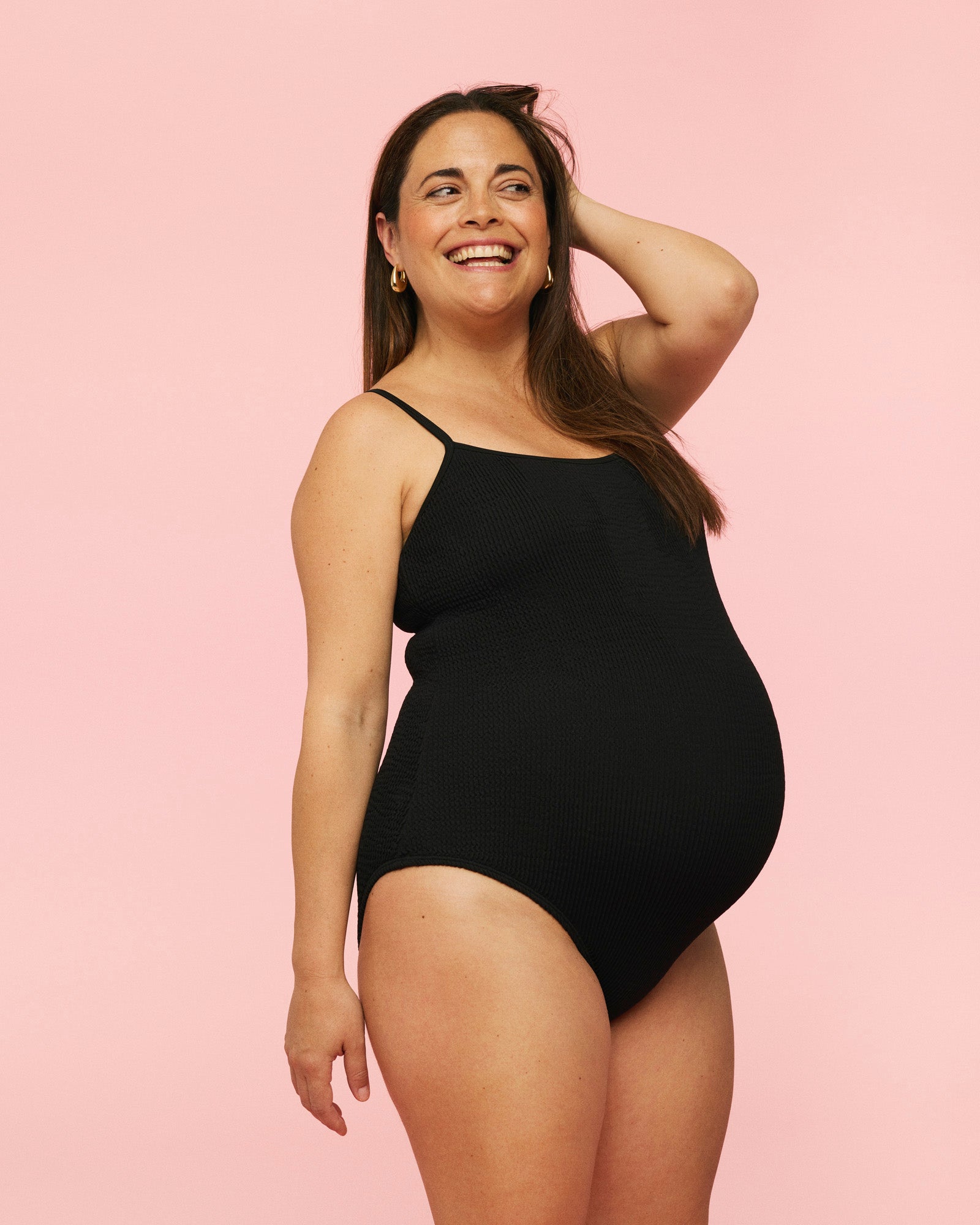 Gravid kvinde som smiler iført momkind gravid badedragt i farven sort.
