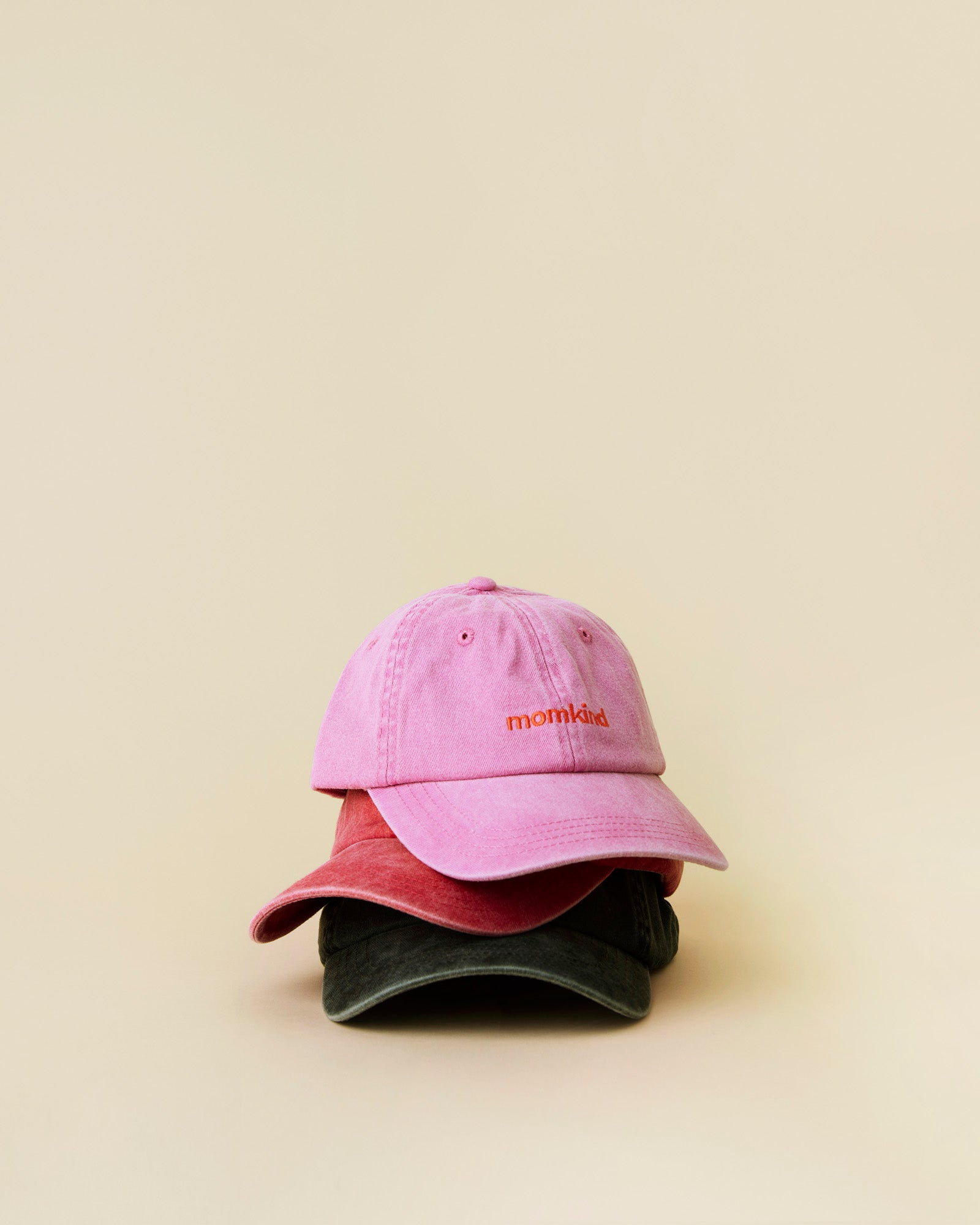 momkind cap I alle tre farver. Lyserød, rød og sort. De er alle tre stablet ovenpå hinanden