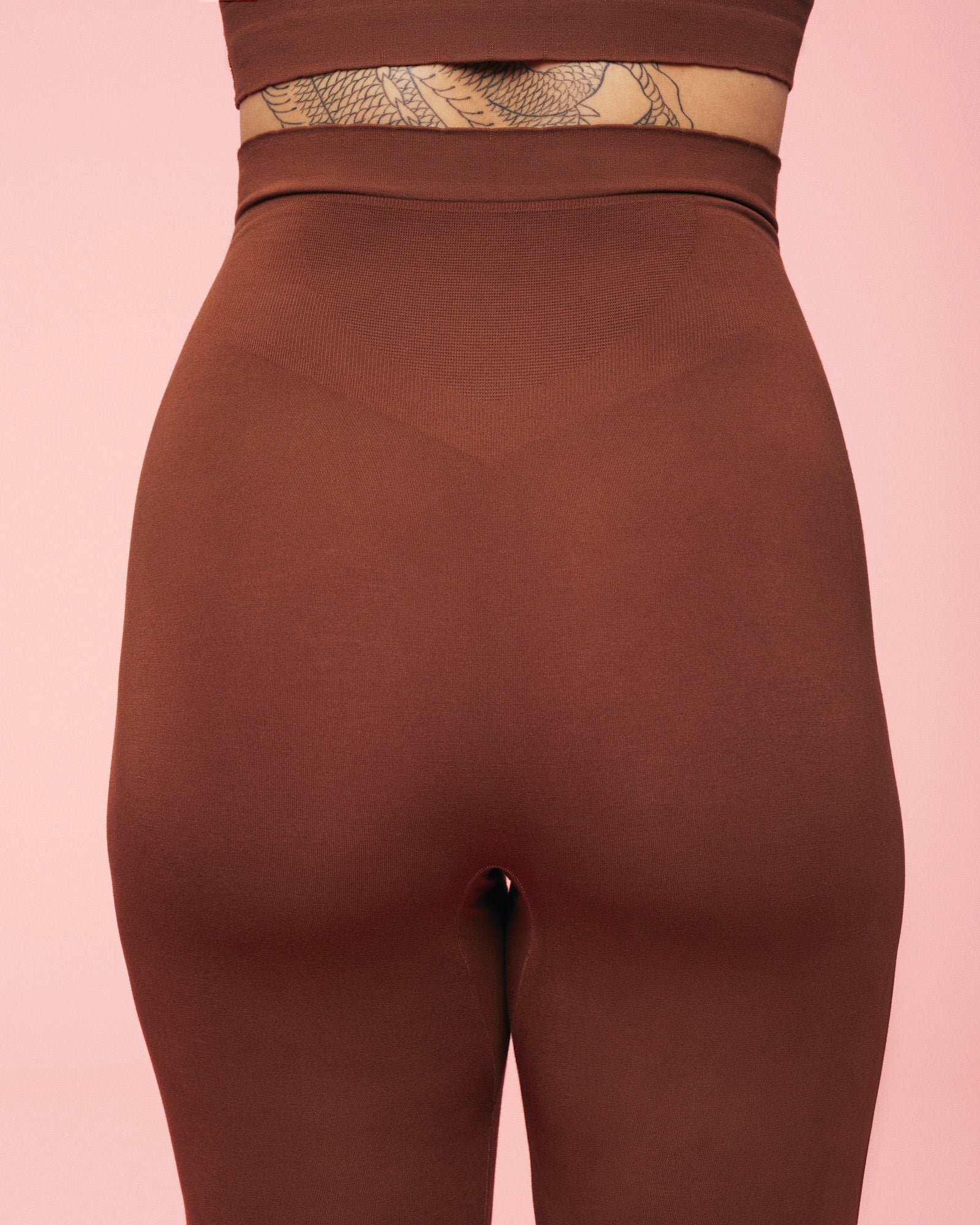 bagdel iført gravid leggings i brun fra momkind hvor man kan se detaljerne af støttepanelerne som giver støtte til lænden