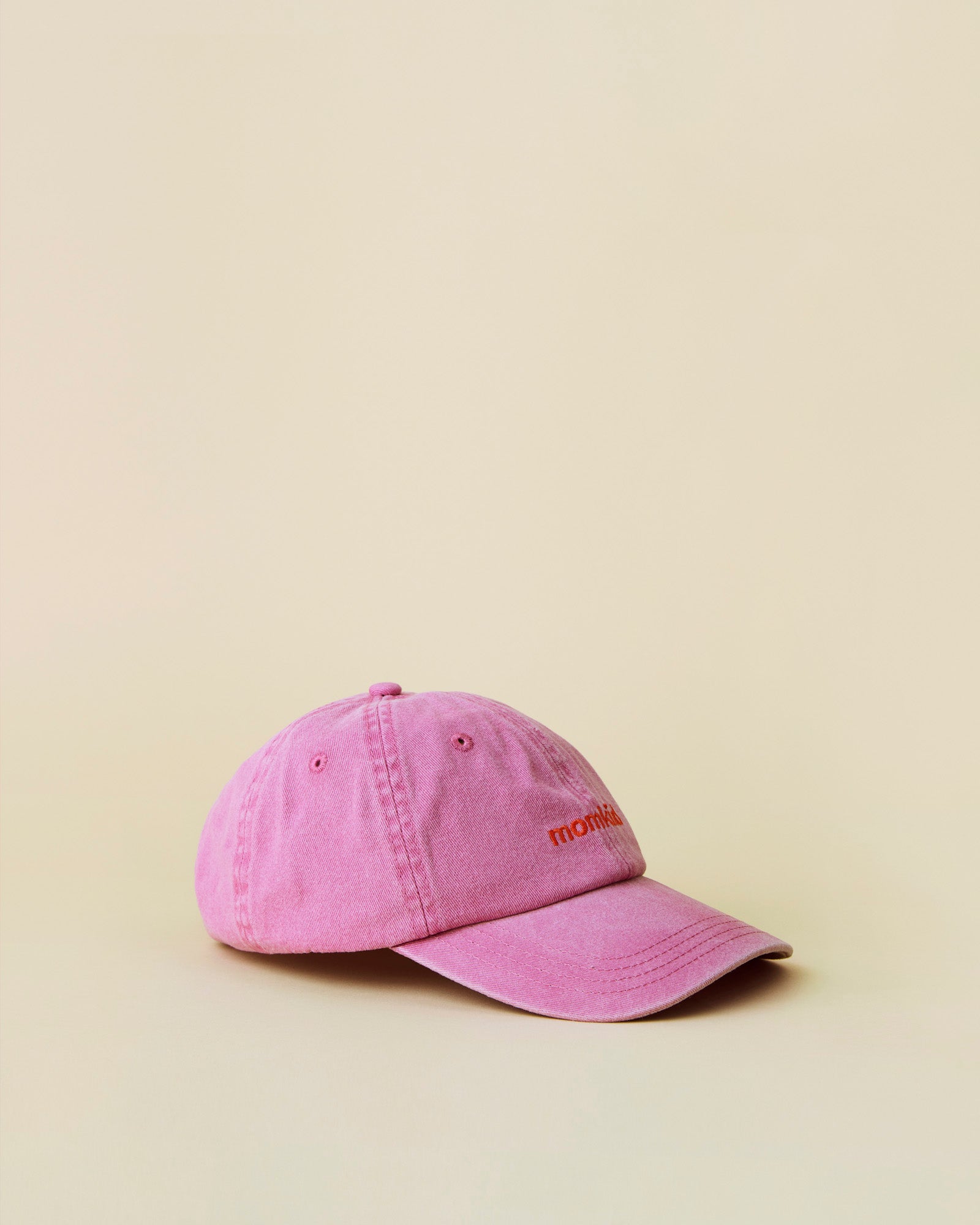 Momkind cap I lyserød med rødt logo. Cap ses fra siden.