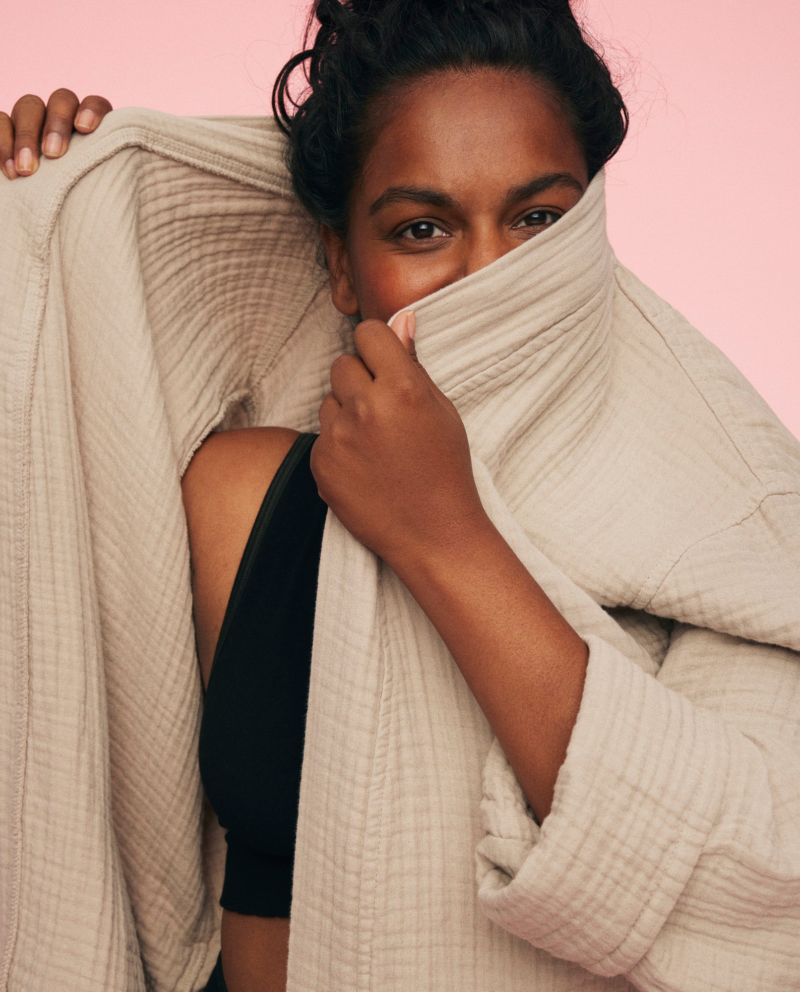 Kvinde er iført momkind morgenkåbe. Hun løfter den op og gemmer ansigtet en smule bag kåben.