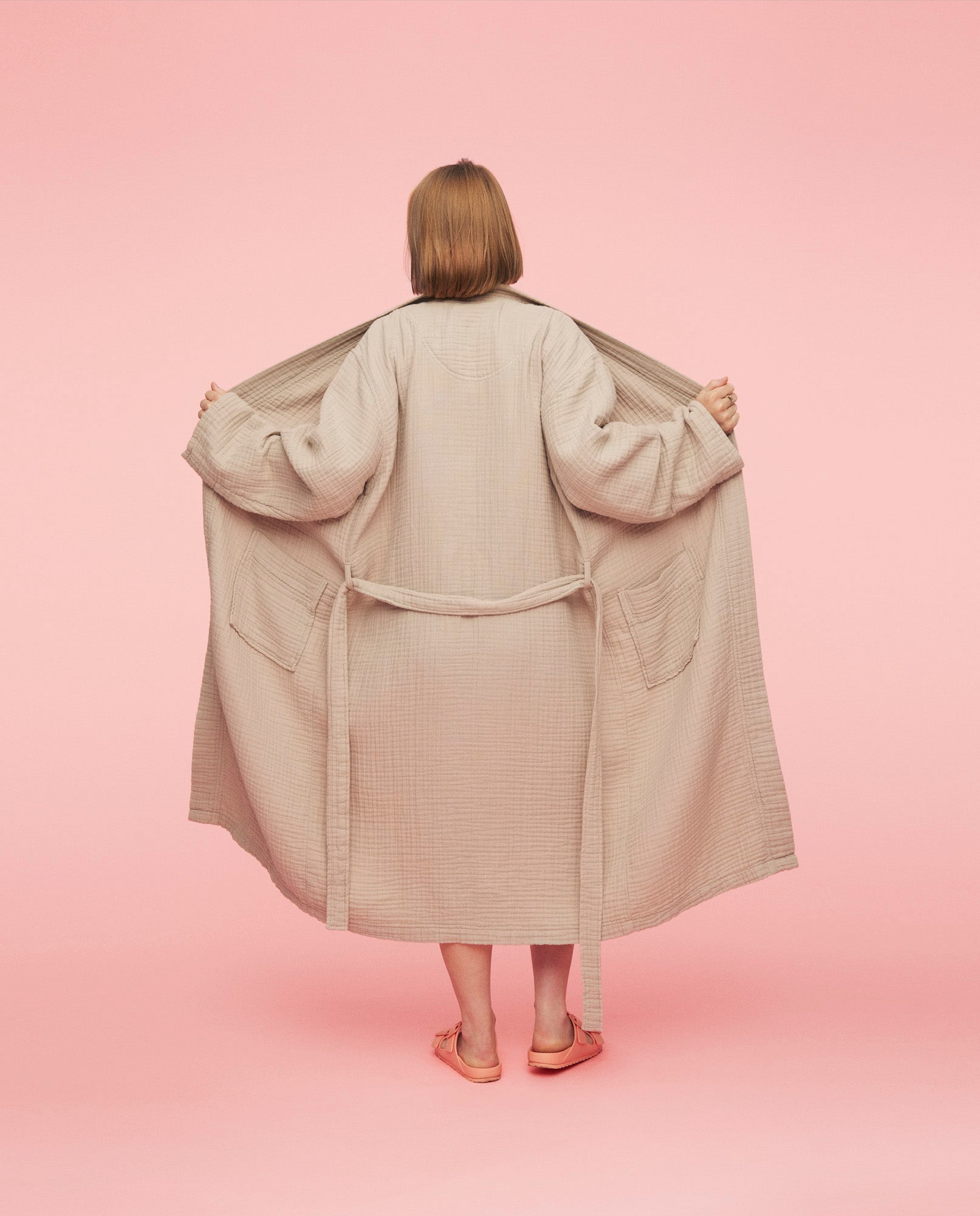 Kvinde står med ryggen til iført morgenkåbe fra momkind. Hun holder den åben så man kan se hele kåben.