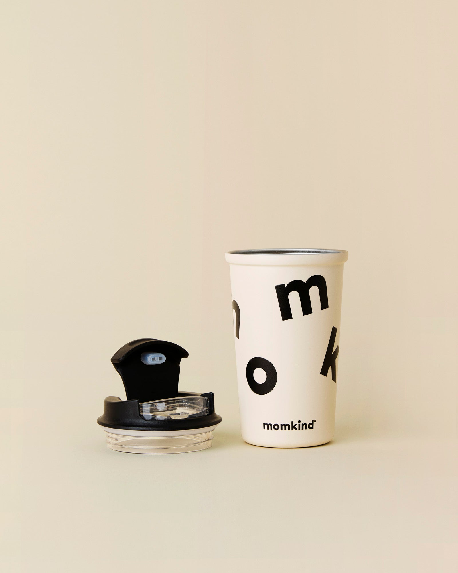 To go termokrus fra momkind I oatmeal. Kruset er i stål og låget ligger åbent ved siden af.