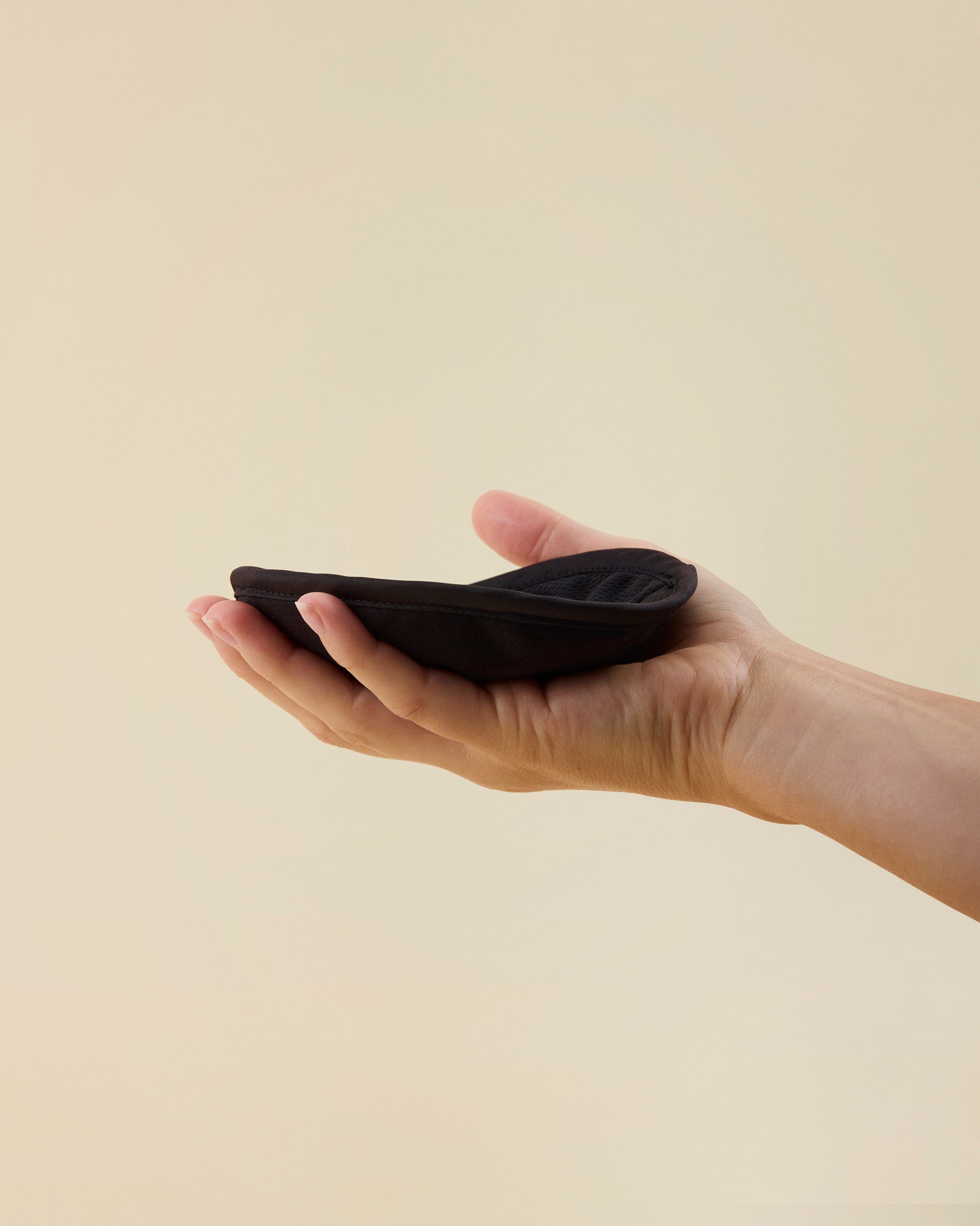 hånd holder et sort genanvendeligt ammeindlæg fra momkind i håndfladen