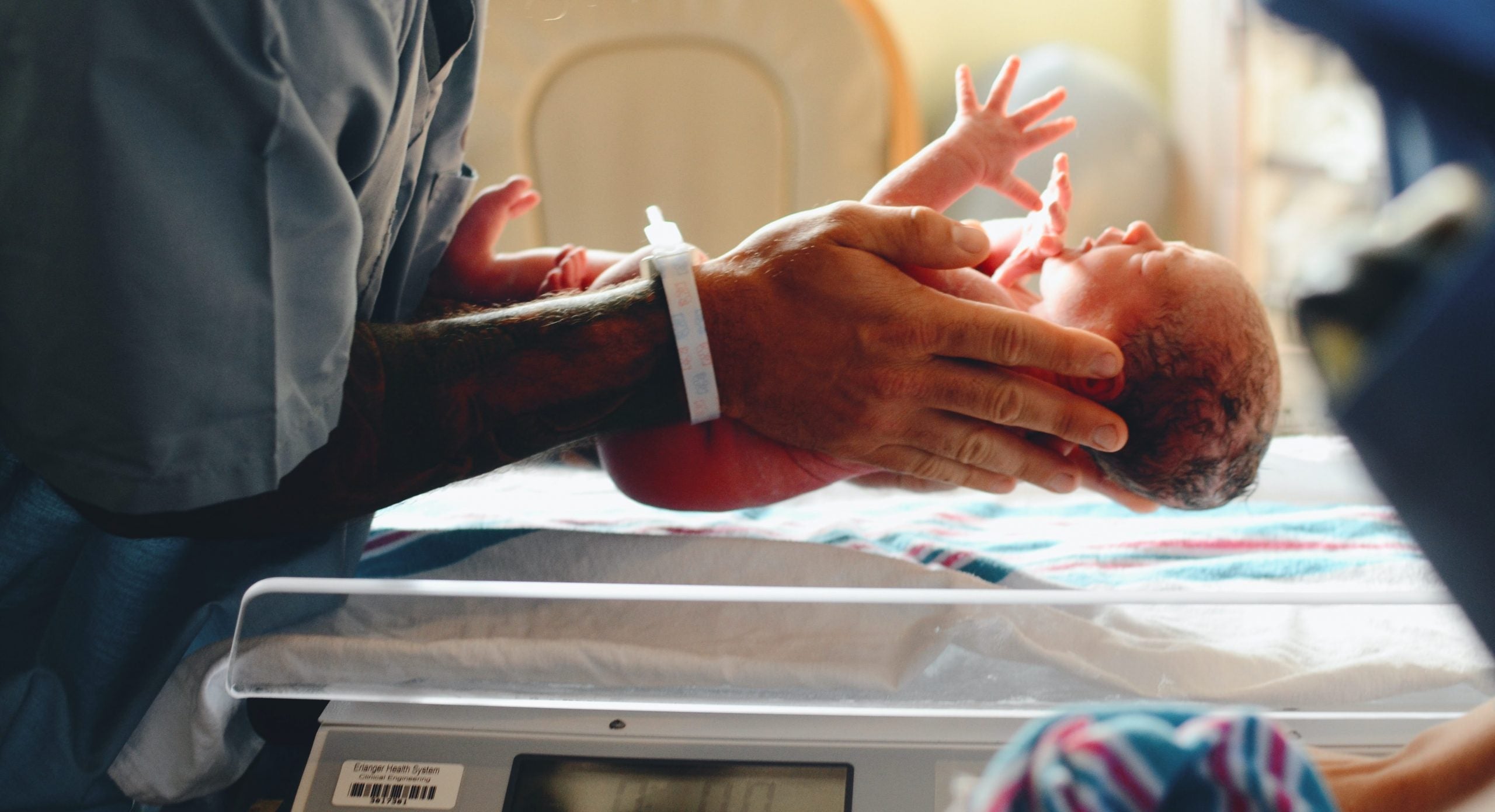 tegn på fødsel nyfødt baby løftes op fra vægt