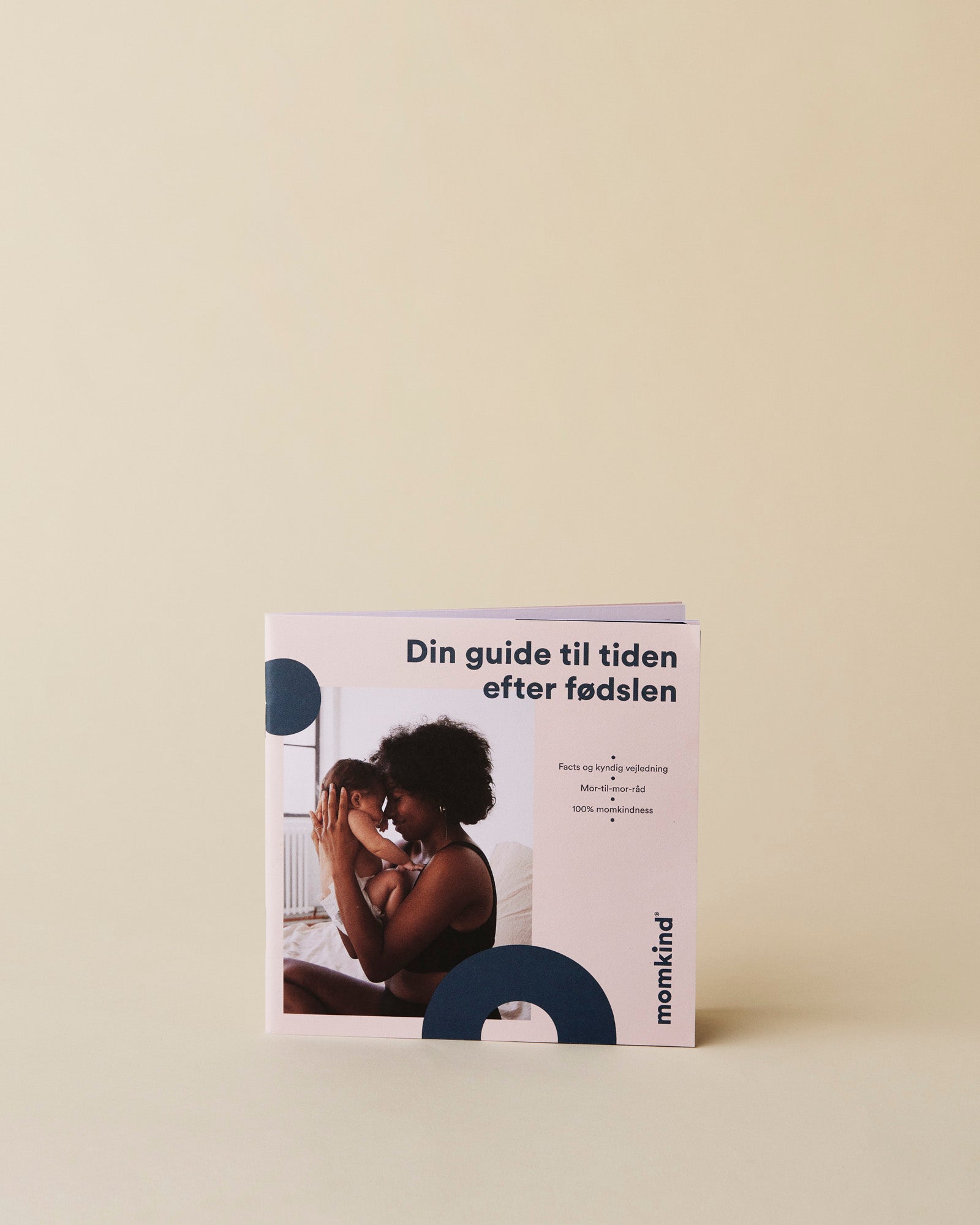 En lille guide til efter fødslen. På billedet sidder en mor og holder sin baby tæt. 