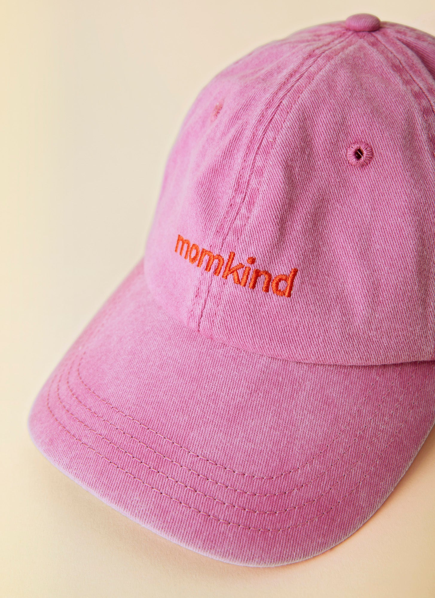 Momkind cap I lyserød og rød logo. Kasket ses helt tæt på fra fronten.