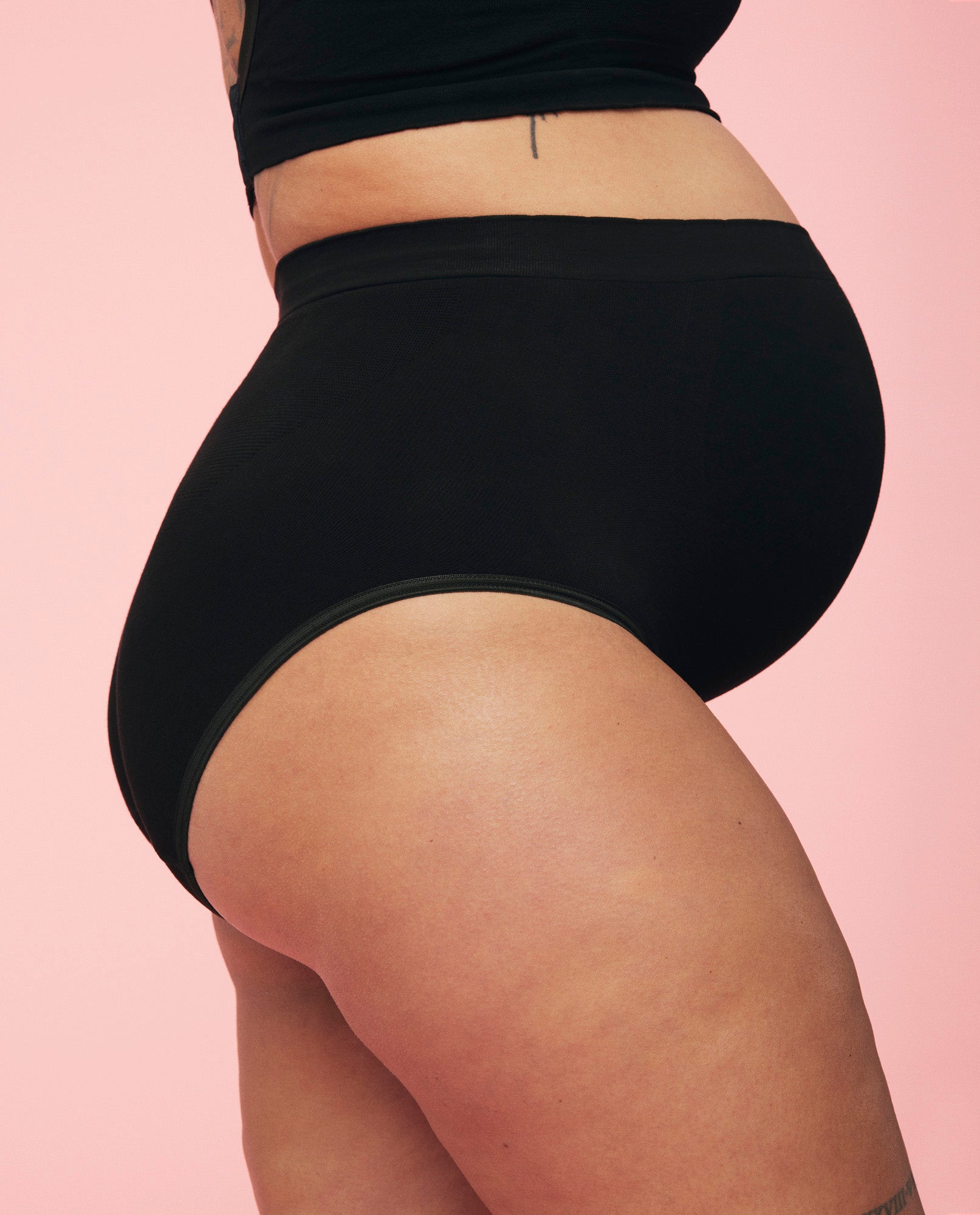 Gravid kvinde iført momkinds belly support graviditetstrusse og amme bh i sort. Billedet viser maven i fokus. 