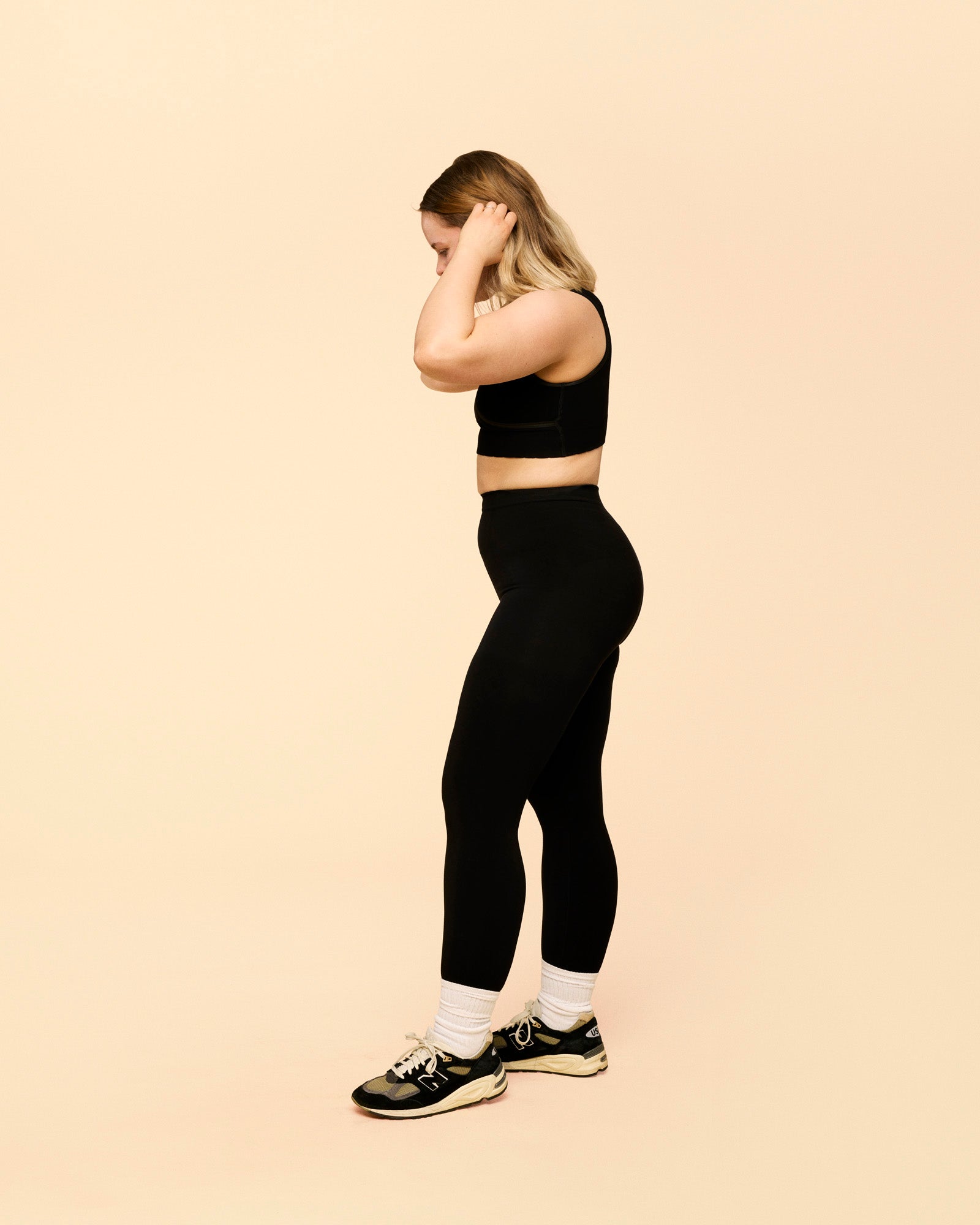 kompression leggings til efter fødslen. Model ses fra siden iført leggings i sort.