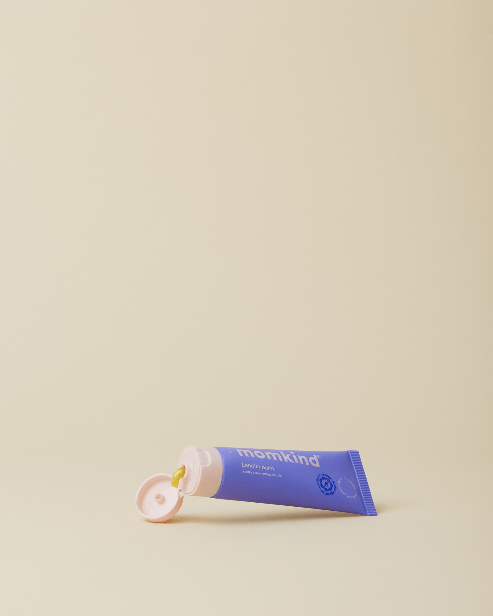 Momkind lanolin salve med åbent låg, hvor en smule salve kommer ud.